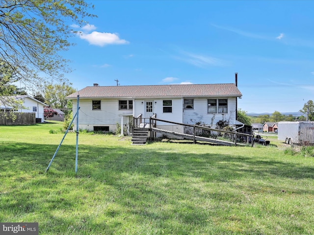 rear view of house with a lawn and fence
