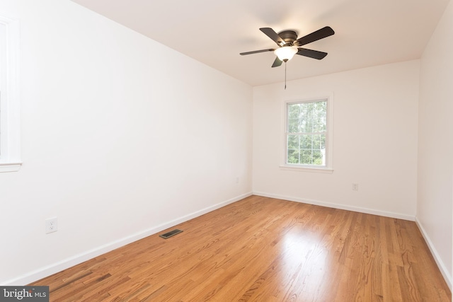 unfurnished room with visible vents, light wood-type flooring, a ceiling fan, and baseboards