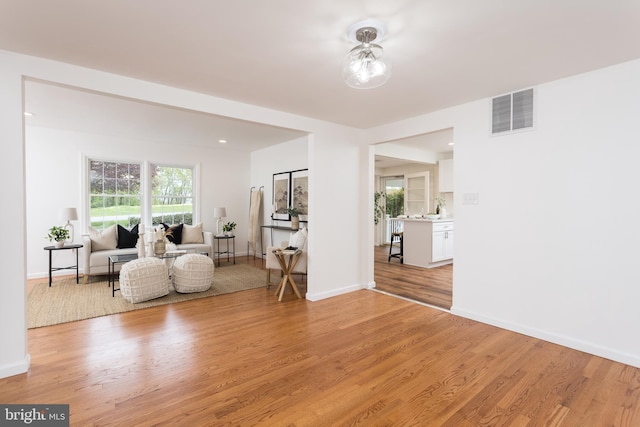 living area featuring visible vents, light wood-style flooring, and baseboards
