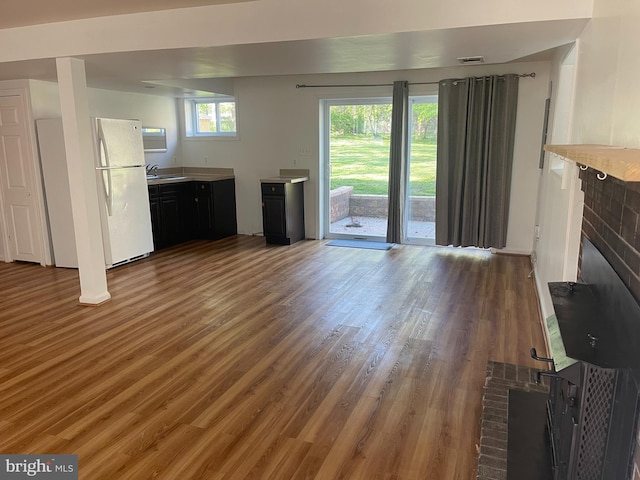 unfurnished living room with a sink, a fireplace, and wood finished floors