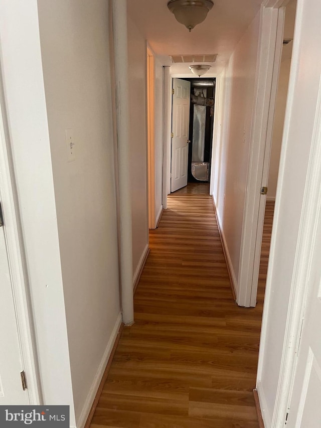 hallway featuring baseboards and wood finished floors