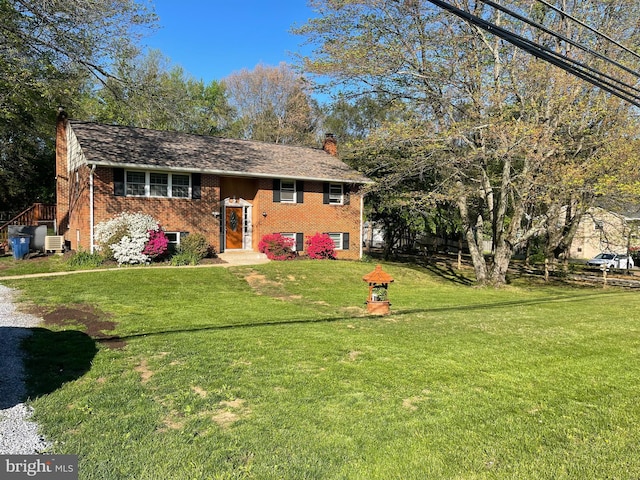 bi-level home with brick siding, a chimney, and a front lawn