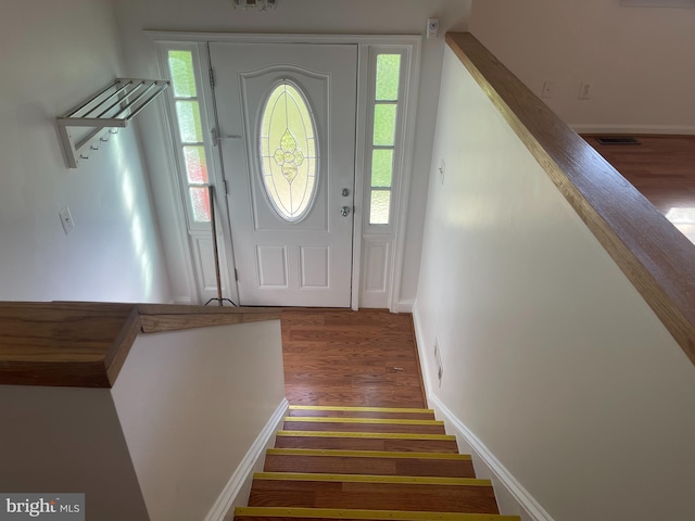 foyer entrance with stairs, baseboards, visible vents, and wood finished floors