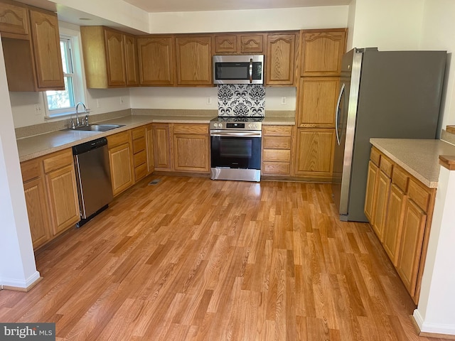 kitchen featuring light wood-style floors, light countertops, brown cabinets, a sink, and stainless steel appliances
