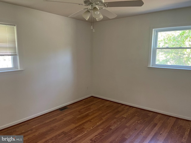 empty room with a healthy amount of sunlight, a ceiling fan, wood finished floors, and visible vents