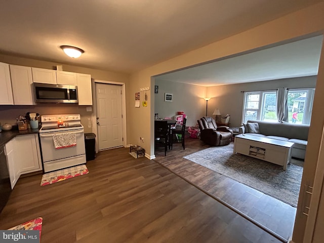 kitchen featuring stainless steel microwave, white electric range oven, white cabinets, dark wood-style flooring, and open floor plan