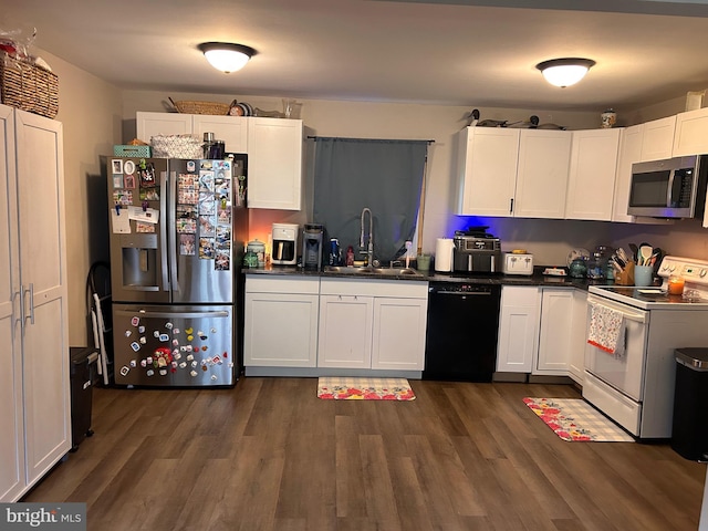 kitchen with stainless steel appliances, a sink, dark countertops, and white cabinets