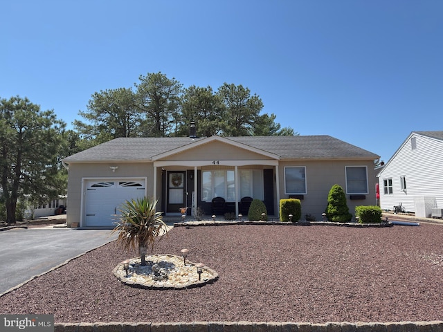 single story home with a garage, aphalt driveway, roof with shingles, and covered porch
