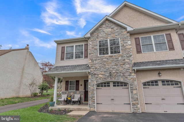 view of front of home with stone siding, stucco siding, covered porch, and aphalt driveway