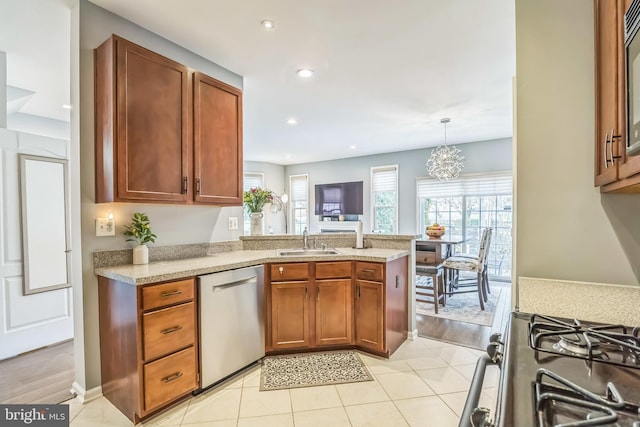 kitchen featuring recessed lighting, appliances with stainless steel finishes, brown cabinets, a sink, and a peninsula