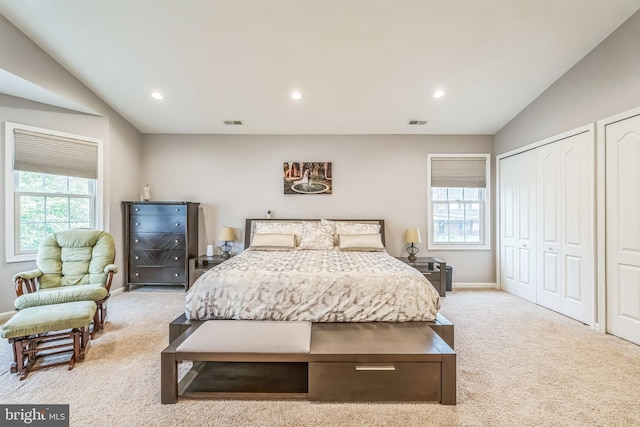 carpeted bedroom with visible vents, multiple closets, baseboards, and multiple windows