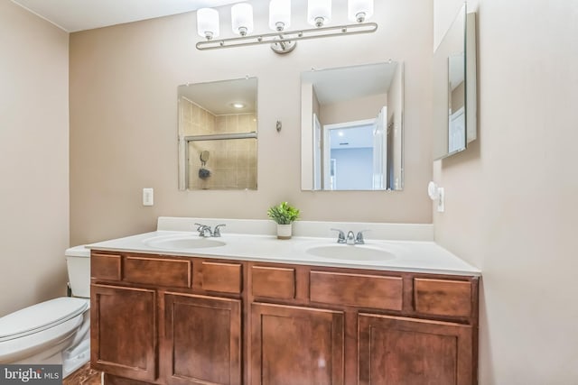 bathroom featuring toilet, a tile shower, double vanity, and a sink