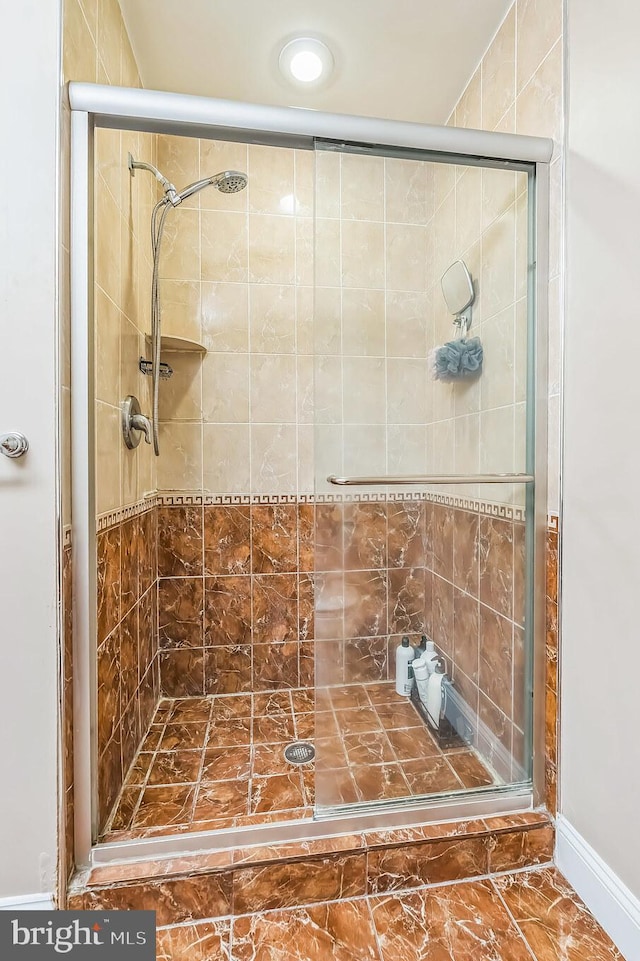 full bathroom with a stall shower and baseboards