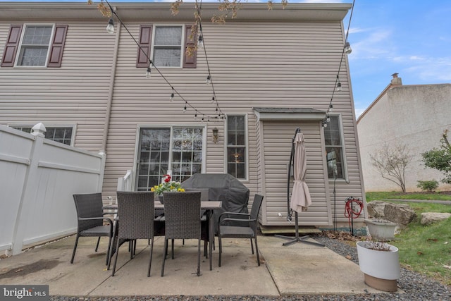 rear view of property with fence, outdoor dining area, and a patio area