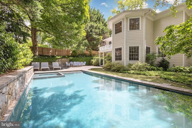 view of swimming pool featuring a patio, a pool with connected hot tub, and fence