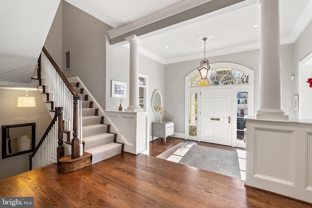 entrance foyer featuring crown molding, wood finished floors, and ornate columns