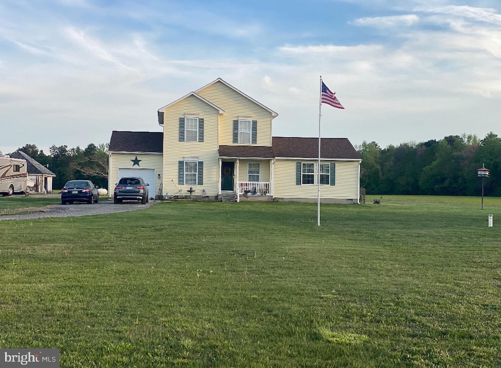 traditional home featuring a porch, a front lawn, gravel driveway, and an attached garage