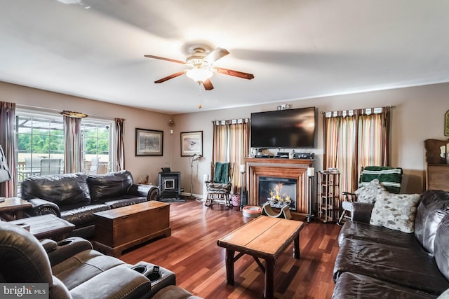 5135 Clark Canning House Rd, Federalsburg, MD 21632 - living room featuring a ceiling fan, a wood stove, dark wood-type flooring, and a lit fireplace