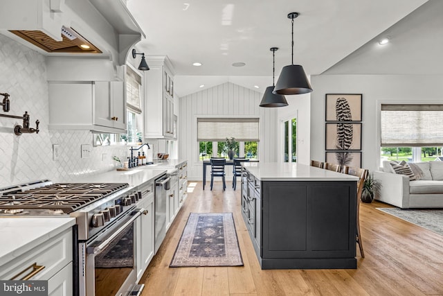 kitchen with vaulted ceiling, white cabinets, appliances with stainless steel finishes, and light countertops