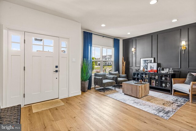 entryway with light wood-style floors, a decorative wall, and recessed lighting