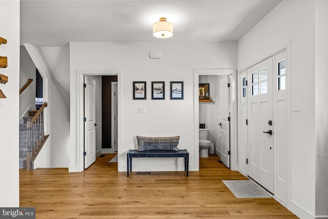 foyer entrance featuring light wood-type flooring, baseboards, and stairs