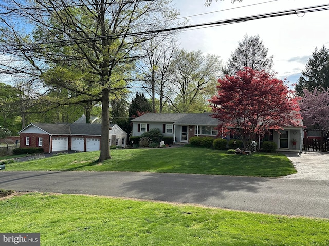 view of front of property featuring a garage, fence, aphalt driveway, and a front yard