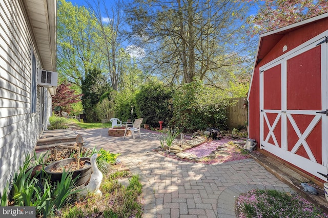 exterior space featuring an outbuilding, a fire pit, fence, and a storage shed