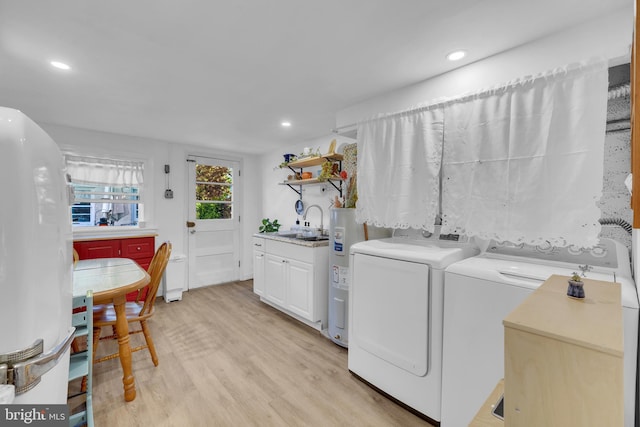 laundry room featuring electric water heater, light wood-type flooring, a sink, recessed lighting, and washer and dryer