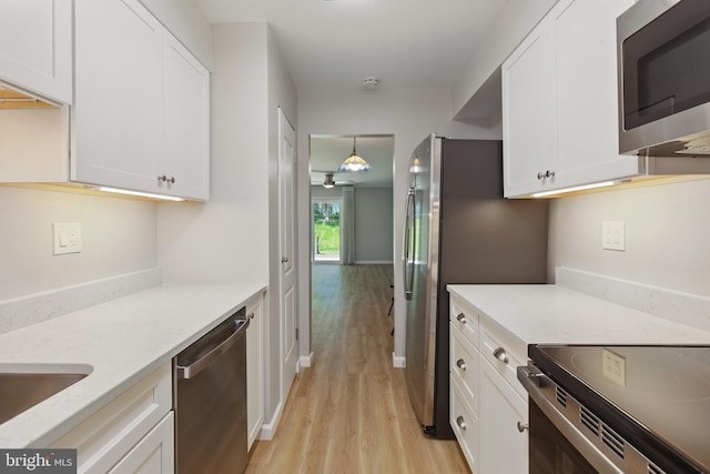 kitchen with light stone countertops, stainless steel appliances, light wood-style flooring, and white cabinetry