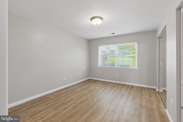 unfurnished bedroom with baseboards, a closet, light wood finished floors, and visible vents
