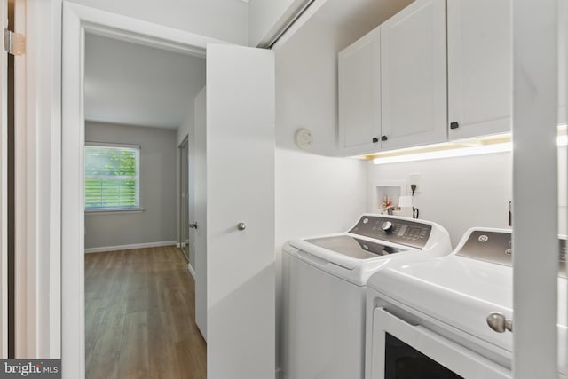 washroom with cabinet space, baseboards, washing machine and dryer, and light wood finished floors