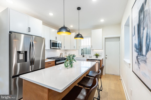 2131 Wharton St, Philadelphia, PA 19146 - kitchen featuring tasteful backsplash, stainless steel appliances, light wood finished floors, and a kitchen breakfast bar