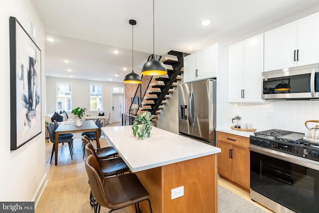 2131 Wharton St, Philadelphia, PA 19146 - kitchen with a kitchen island, a kitchen bar, light wood-style flooring, appliances with stainless steel finishes, and hanging light fixtures