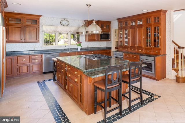 kitchen with a sink, light tile patterned floors, brown cabinetry, and stainless steel appliances