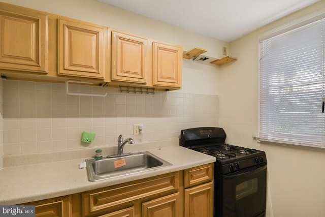 kitchen featuring black gas range, a sink, decorative backsplash, and light countertops