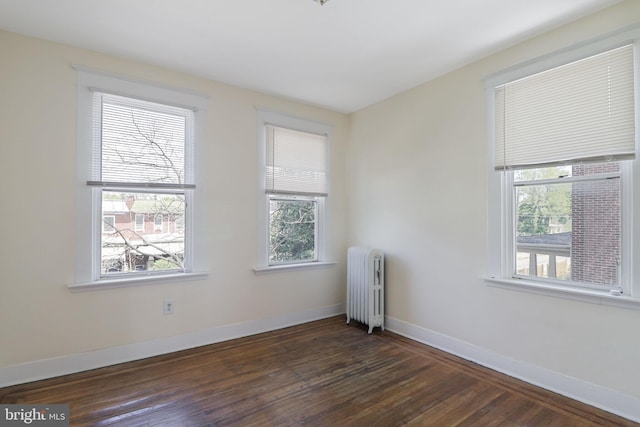 unfurnished room featuring baseboards, dark wood finished floors, radiator heating unit, and a healthy amount of sunlight