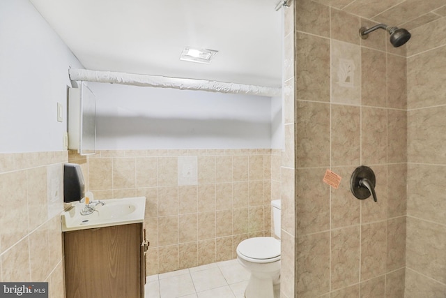 full bathroom with tile patterned flooring, vanity, toilet, tile walls, and tiled shower