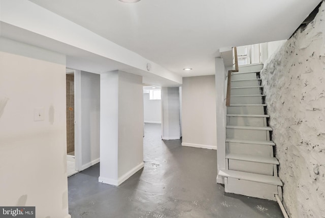 basement featuring baseboards and stairway