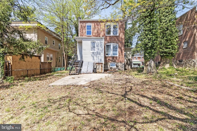back of house featuring brick siding, fence, and a patio