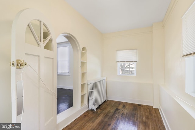 spare room featuring radiator, baseboards, and hardwood / wood-style flooring