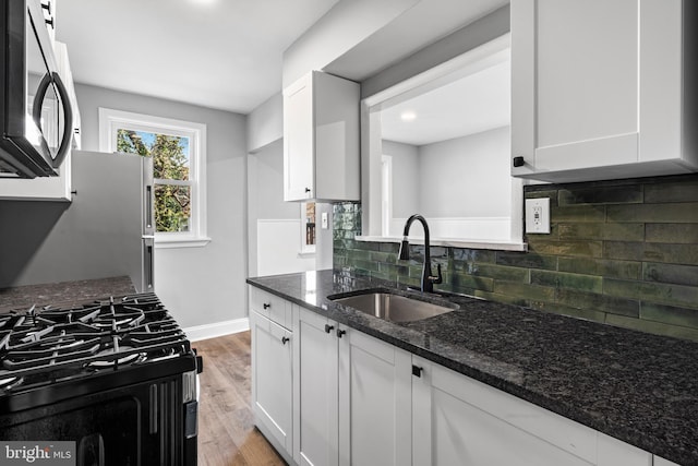kitchen featuring a sink, white cabinetry, black range with gas stovetop, and light wood-type flooring