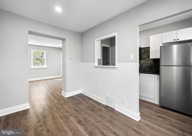 kitchen with white cabinets, visible vents, freestanding refrigerator, dark wood-style flooring, and wainscoting