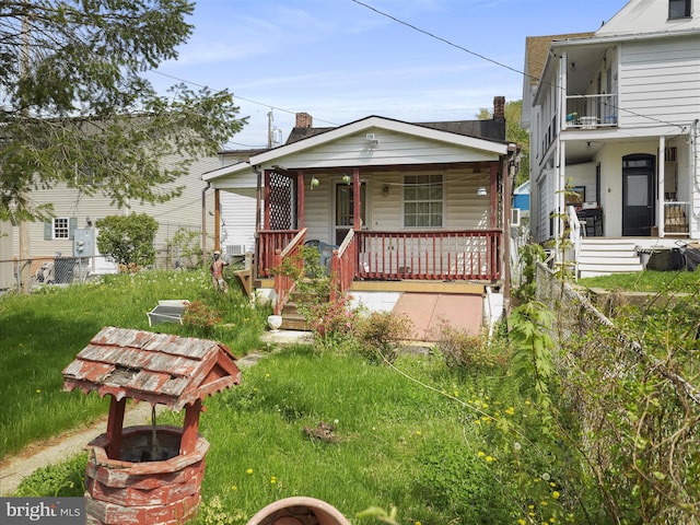 view of front of home with covered porch, fence, and a front lawn