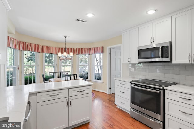 1602 Blacksmith Ln, Herndon, VA 20170 - kitchen featuring appliances with stainless steel finishes, a chandelier, white cabinetry, light wood-type flooring, and tasteful backsplash