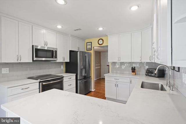 1602 Blacksmith Ln, Herndon, VA 20170 - kitchen featuring appliances with stainless steel finishes, a sink, white cabinets, decorative backsplash, and recessed lighting