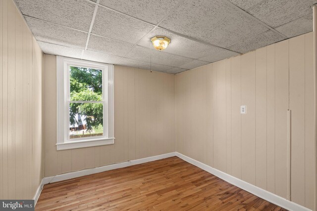 916 N Kresson St, Baltimore, MD 21205 - unfurnished room featuring baseboards, wood finished floors, wooden walls, and a drop ceiling