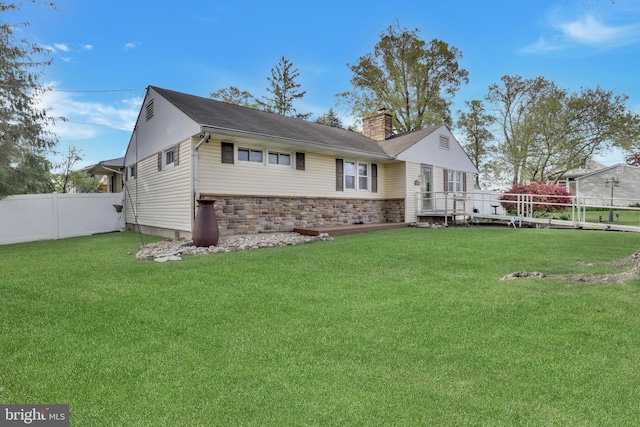 view of front of home with brick siding, fence, a chimney, and a front lawn