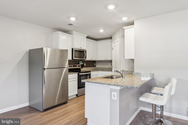 17026 Rollins Rd, Bowling Green, VA 22427 - kitchen with a sink, a peninsula, stainless steel appliances, a breakfast bar area, and visible vents