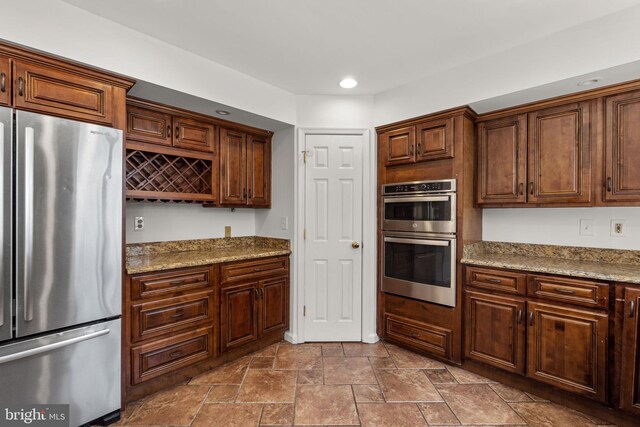kitchen with recessed lighting, stone finish flooring, light stone countertops, and stainless steel appliances