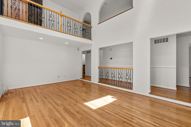 unfurnished living room with baseboards, a high ceiling, and wood finished floors